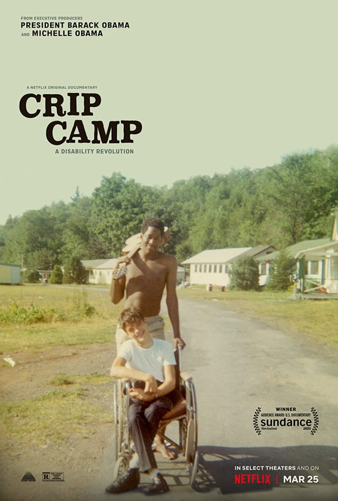The film poster showing a wheelchair user smiling. Behind him, a man is holding on to his wheelchair, a guitar over his shoulder. They are in a camp area with forest and cabins in the background.