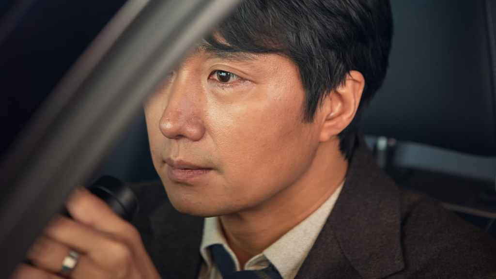 Jang Hae-joon (Park Hae-il) in a car, holding binoculars.