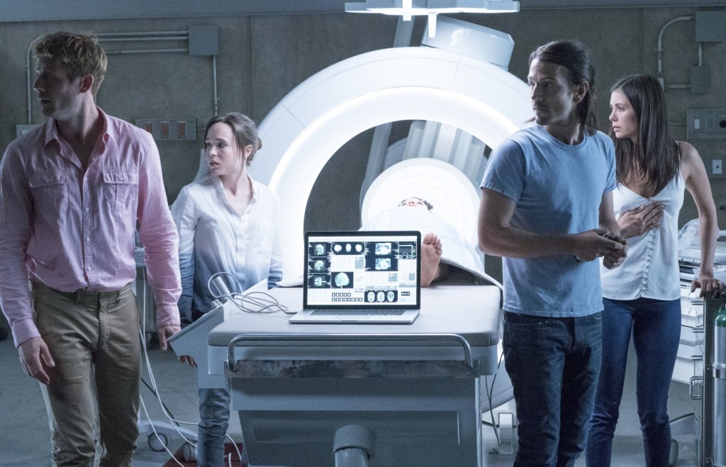 Jamie (James Norton), Courtney (Elliot Page), Ray (Diego Luna) and Marlo (Nina Dobrev) standing around a CT scanner in which Sophia (Kiersey Clemons) is lying.