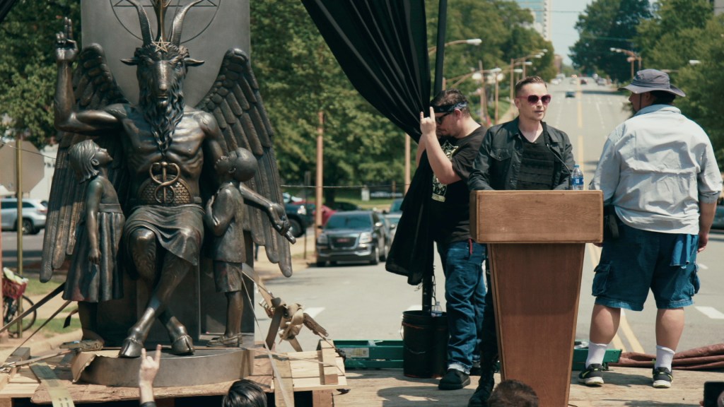 Lucien Greaves giving a speech next to the statue of Baphomet.