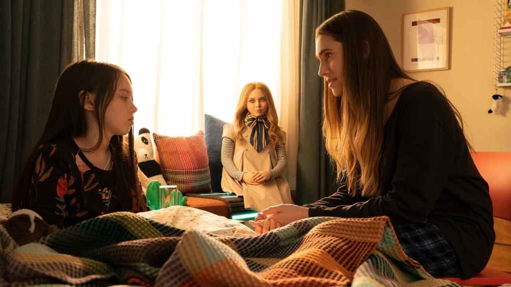 Cady (Violet McGraw) talking to her aunt Gemma (Allison Williams) as M3GAN (Amie Donald) watches.