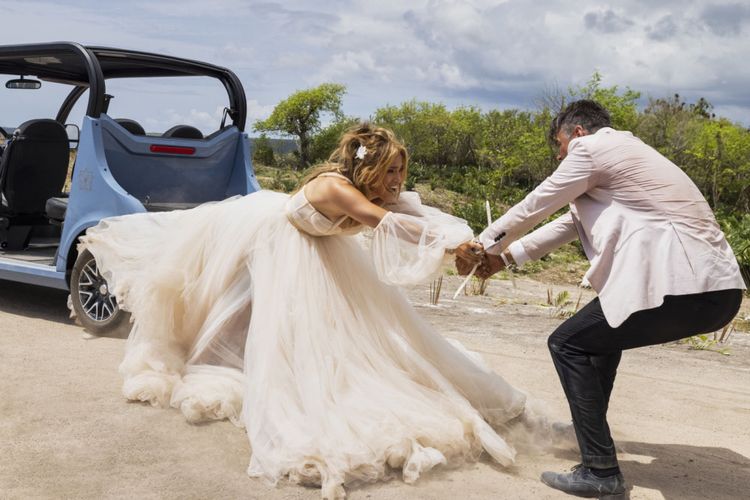 Tom (Josh Duhamel) holding desperately on to Darcy (Jennifer Lopez) whose wedding dress is caught in a golf buggy that is pulling her backwards.