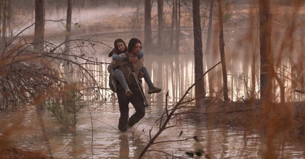 Mills (Adam Driver) carrying Koa (Ariana Greenblatt) through a swamp.