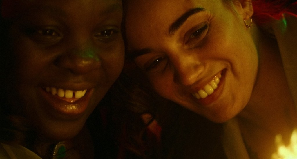 Alma (Déborah Lukumuena) and Margot (Souheila Yacoub) smiling together, their heads close.