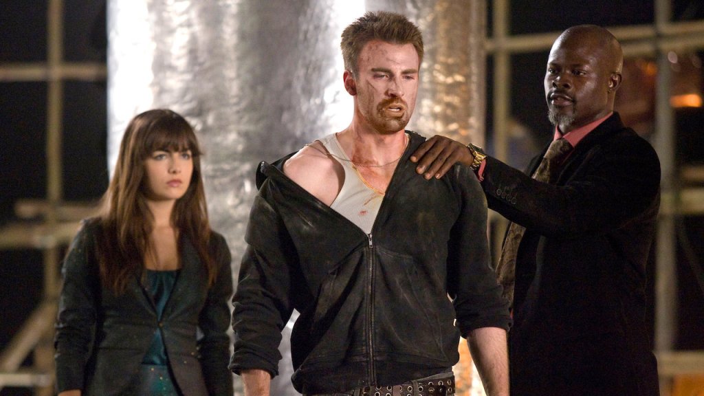 Carver (Djimon Hounsou) holding a beat-up looking Nick (Chris Evans) by the shoulder. Kira (Camilla Belle) is standing behind them.