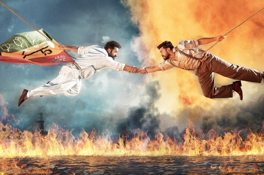 Bheem (N.T. Rama Rao Jr.) and Raju (Ram Charan) hanging from a rope over water that is burning, clasping hands. 