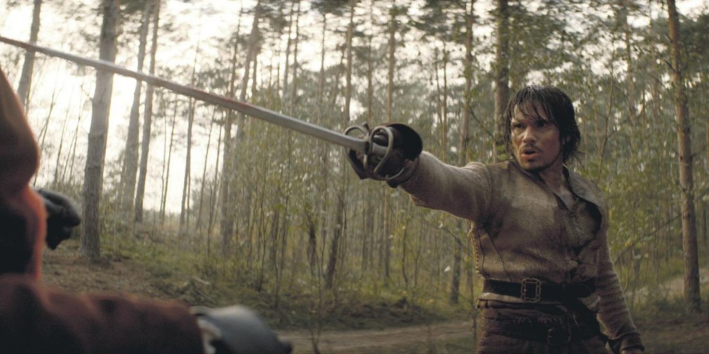 D'Artagnan (François Civil) pointing his sword in the middle of a fight.