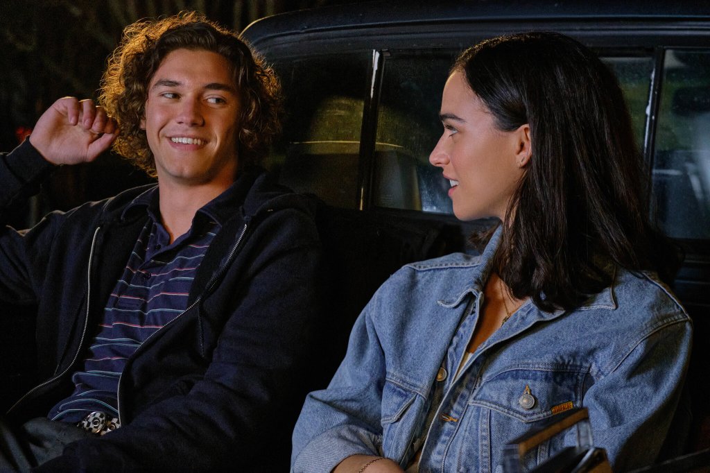 Auden (Emma Pasarow) and Eli (Belmont Cameli) in the bed of a truck, smiling at each other.