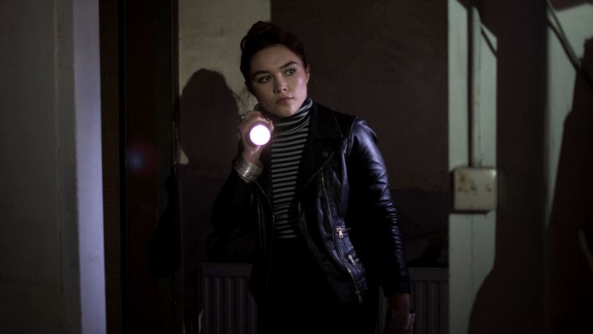 Angela (Florence Pugh) exploring the house with a flashlight.