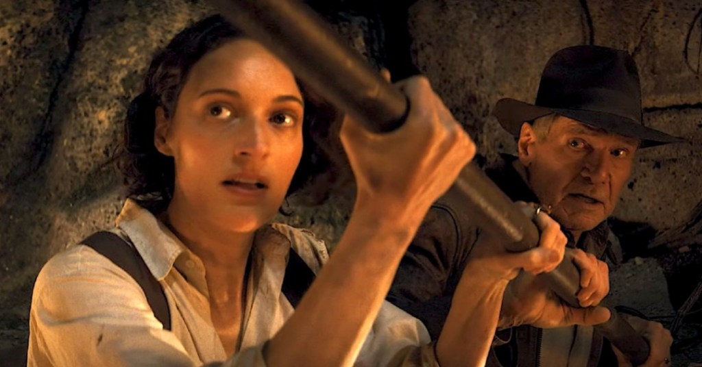 Helena (Phoebe Waller-Bridge) and Indy (Harrison Ford) holding on to metal pole. 