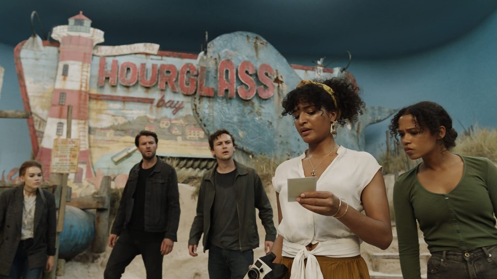 The players looking at a hint in a beach scene. 