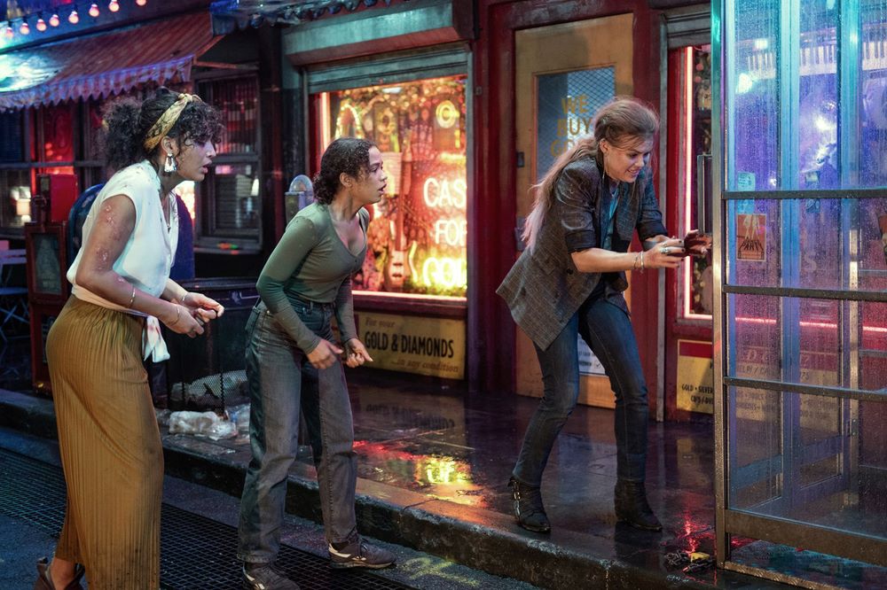 Brianna (Indya Moore), Zoey (Taylor Russell) and Rachel (Holland Roden) on a wet street in front of a phone booth.