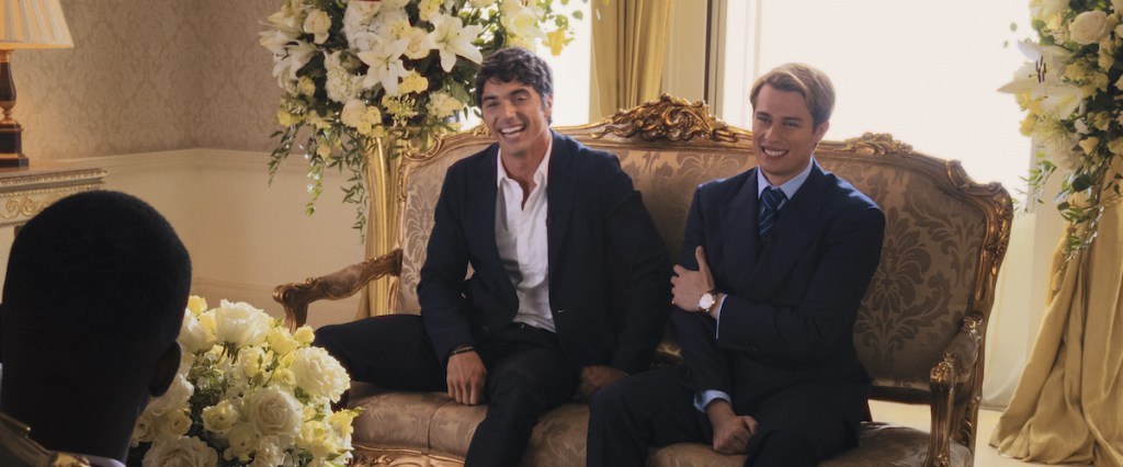 Alex (Taylor Zakhar Perez) and  Henry (Nicholas Galitzine) sitting on a sofa, laughing as they give an interview.