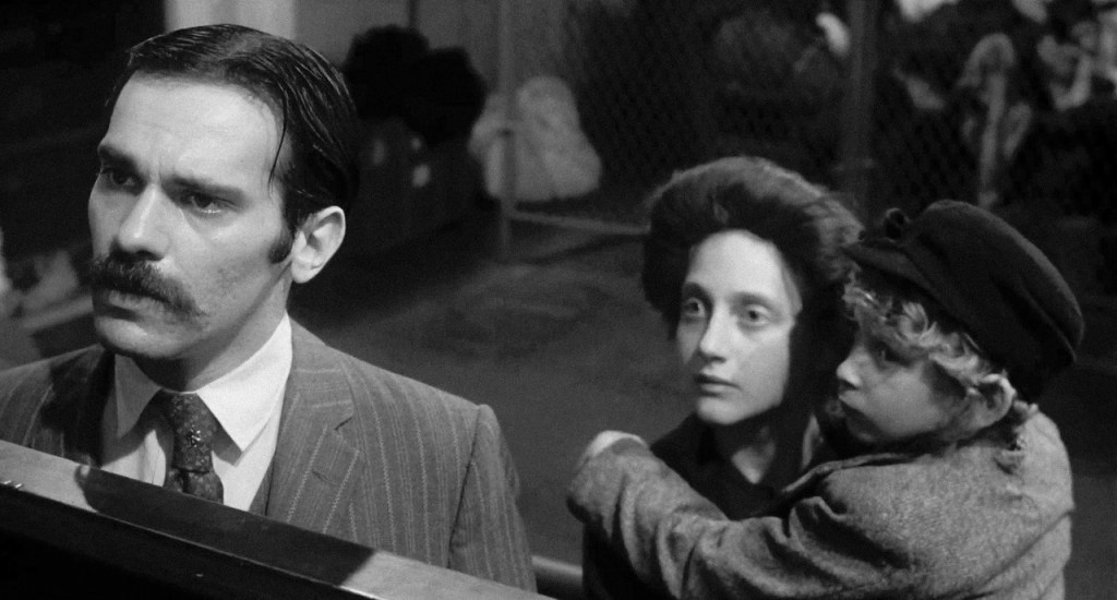 Jake (Steven Keats) and Gitl (Carol Kane) with their little son at the immigration counter.