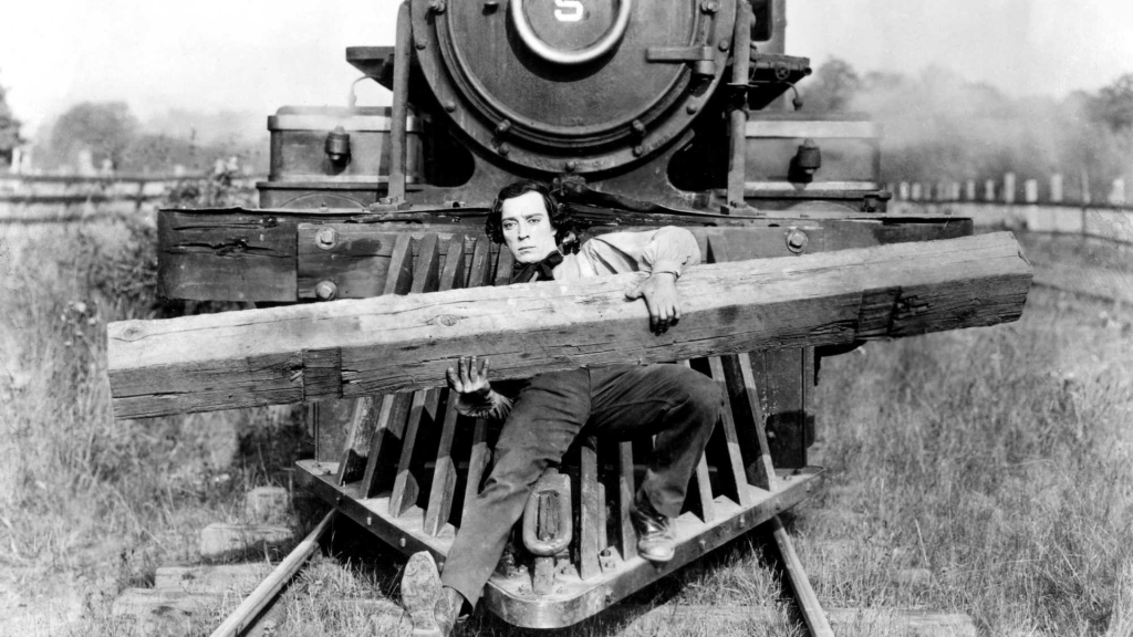 Johnnie (Buster Keaton) braced on the front of the train, holding a giant log.