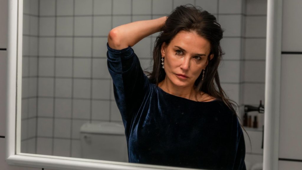 Elisabeth (Demi Moore) looking at herself in the mirror rather critically, her make-up smudged.