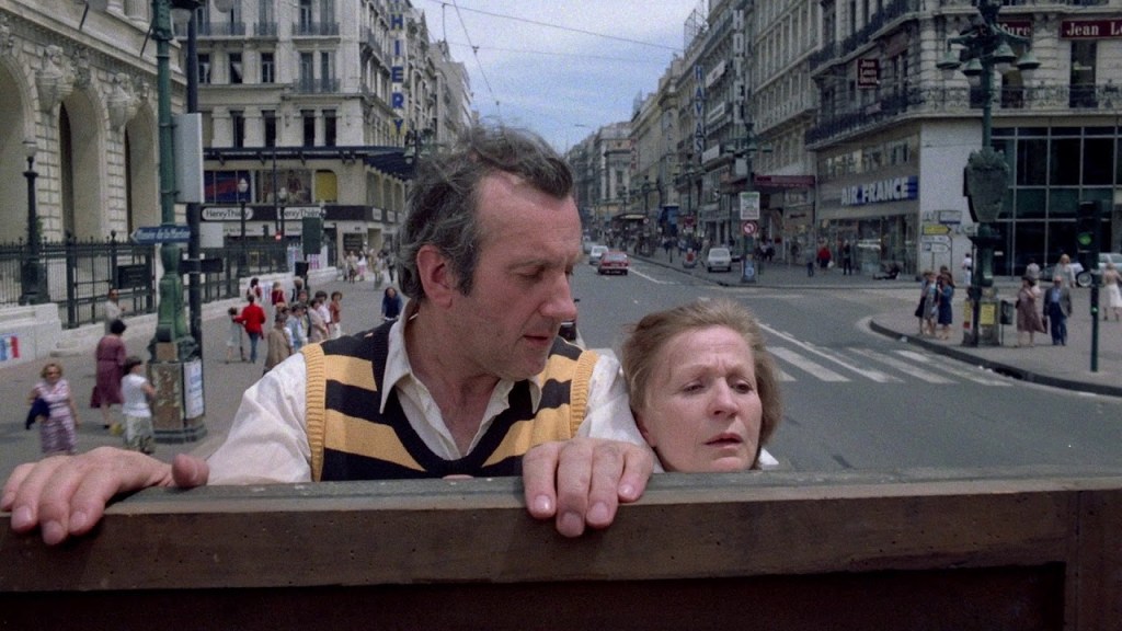 Charles (Daniel Ceccaldi) and Lucie (Ginette Garcin) holding on to the back of a truck.