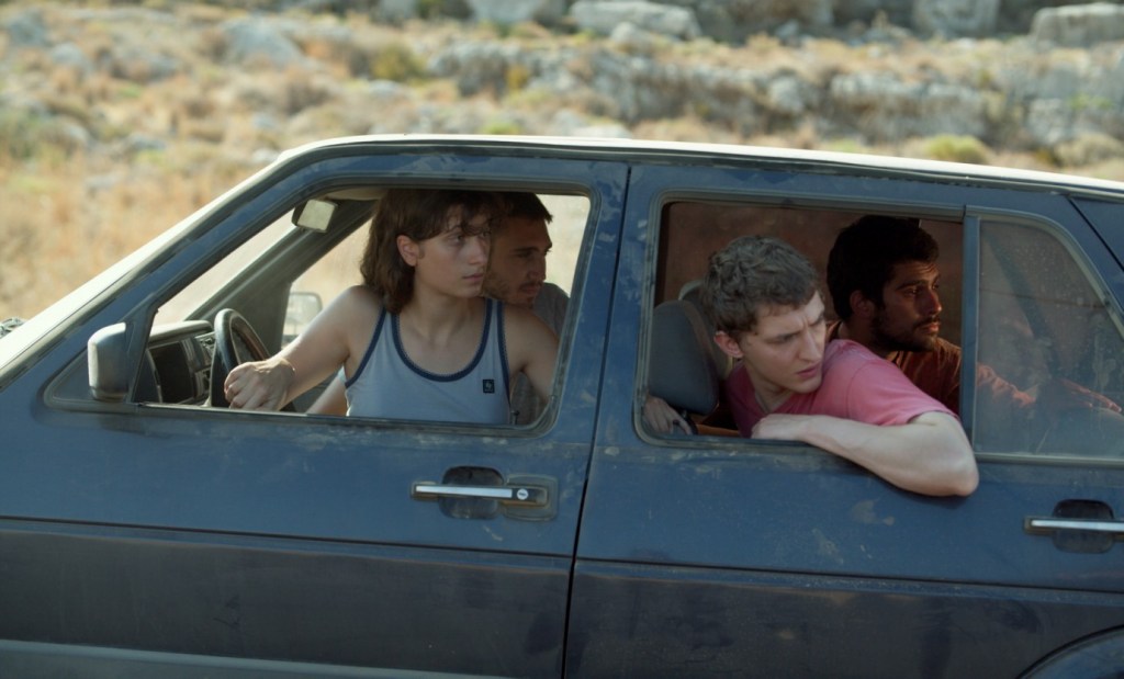 Jon (Aliocha Schneider) in a car with his friends. They are all looking to the rear.