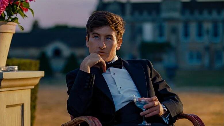 Oliver (Barry Keoghan) lounging in a chair outside, a champagne glass in hand.
