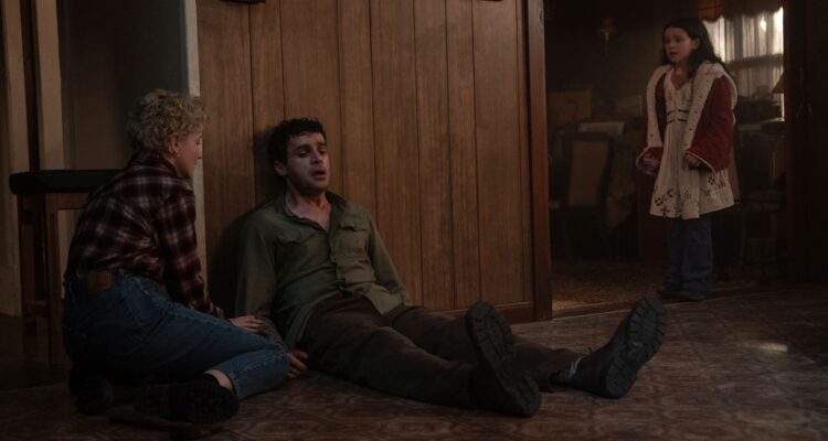 Blake (Christopher Abbott) sitting on the floor, looking ill with Charlotte (Julia Garner) and Ginger (Matilda Firth) looking at him in worry.