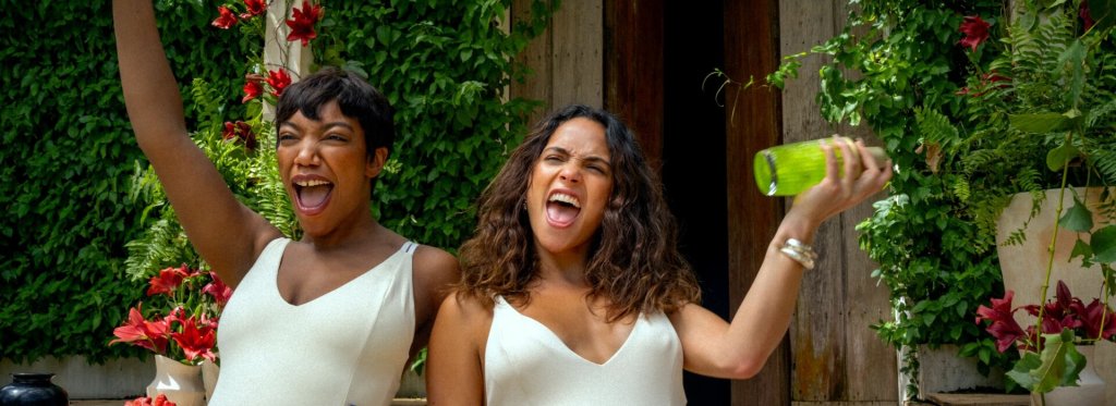 Frida (Naomi Ackie) and Sarah (Adria Arjona) in party mood, shaking a cocktail shaker.