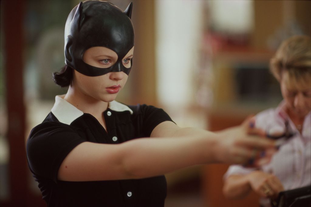 Enid (Thora Birch) wearing a catwoman-ish mask, aiming something toygun like.
