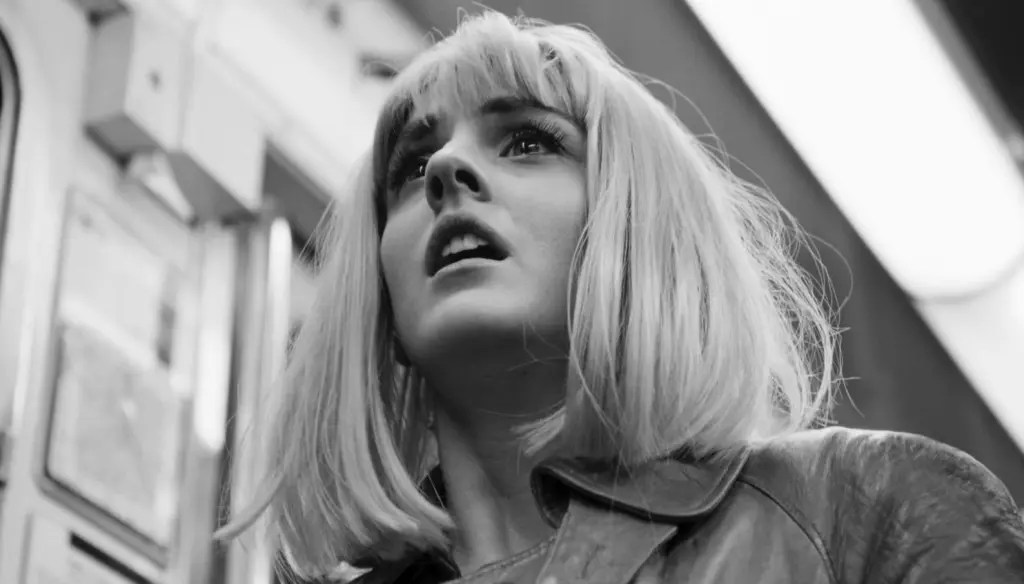 Nora (Noémie Merlant) in the subway, wearing a blond wig, looking distraught.