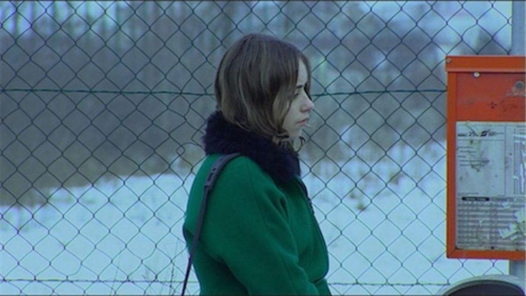 Rita (Barbara Osika) standing at a bus stop in winter.