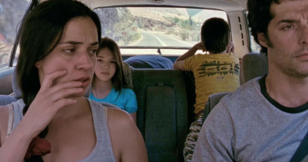 The family driving in the car. Everybody is looking serious and they aren't looking at each other.