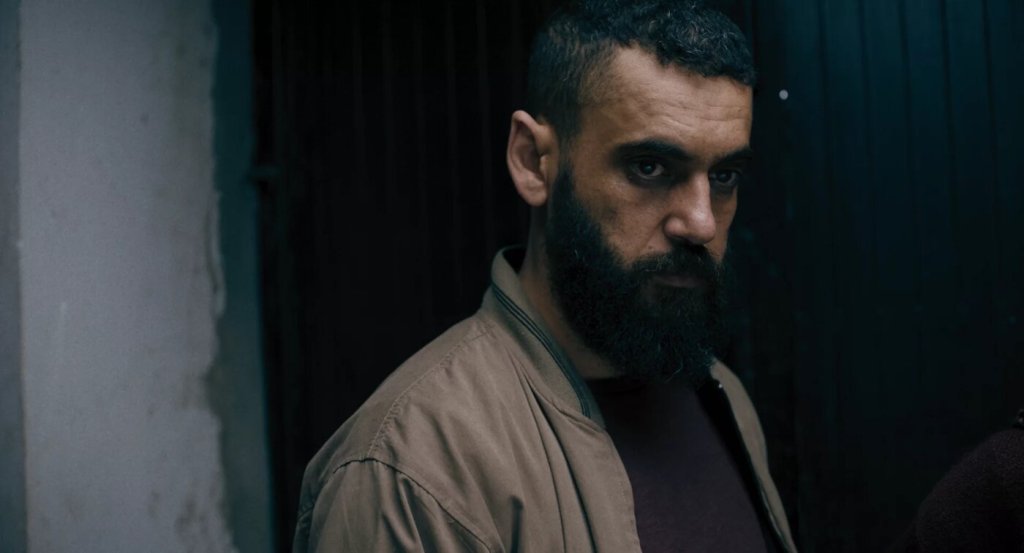 Raqi's disciple (Akram Dieghim) looking serious.