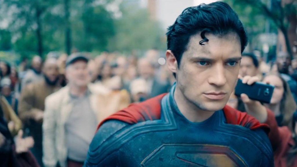 Superman (David Corenswet) looking dirty and grim, a crowd of people behind him. 