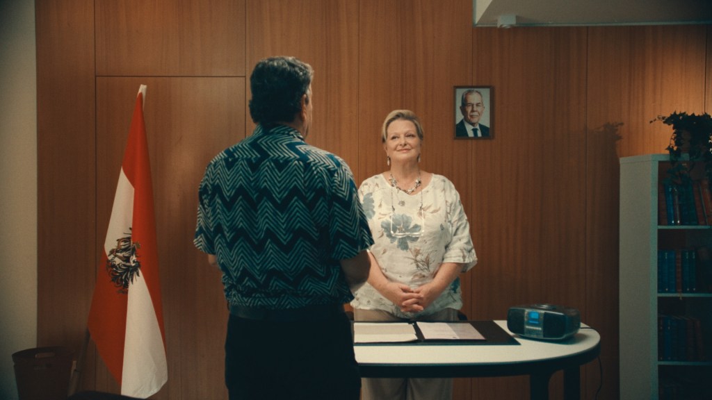 A magistrate stands with a citizenship applicant as they listen to the Austrian hymn before the applicant can be sworn in and receive their citizenship.