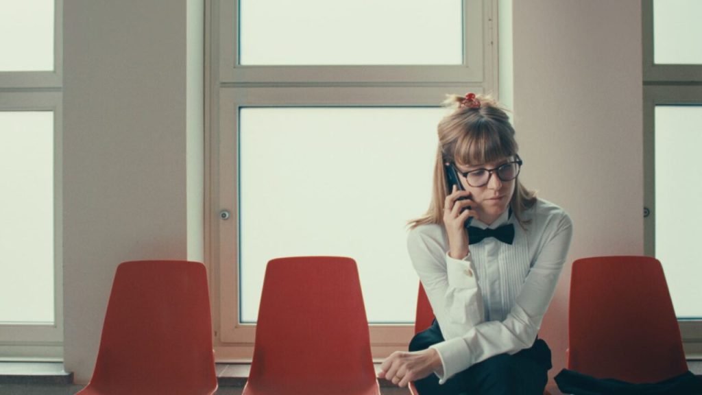 Olga Kosanović in a waiting area, on the phone.