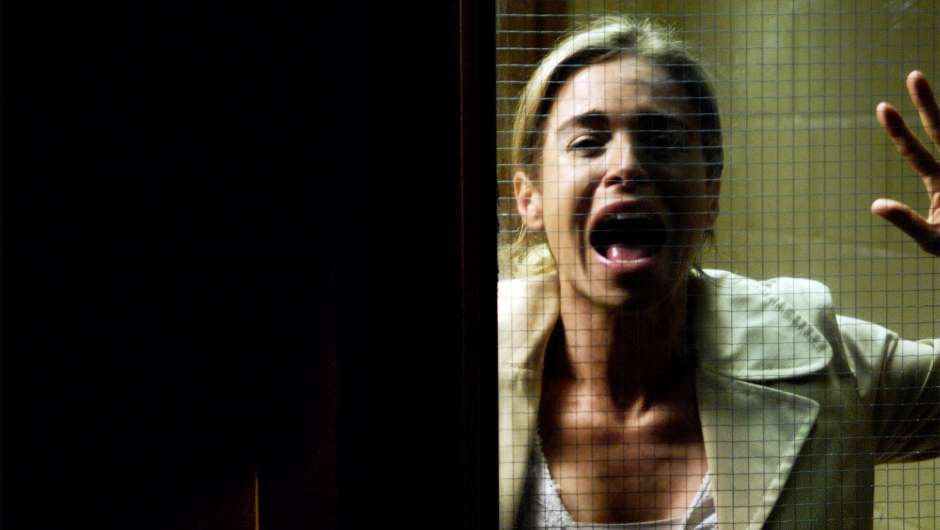 Jill (Betsy Russell) screaming behind a glass door. 