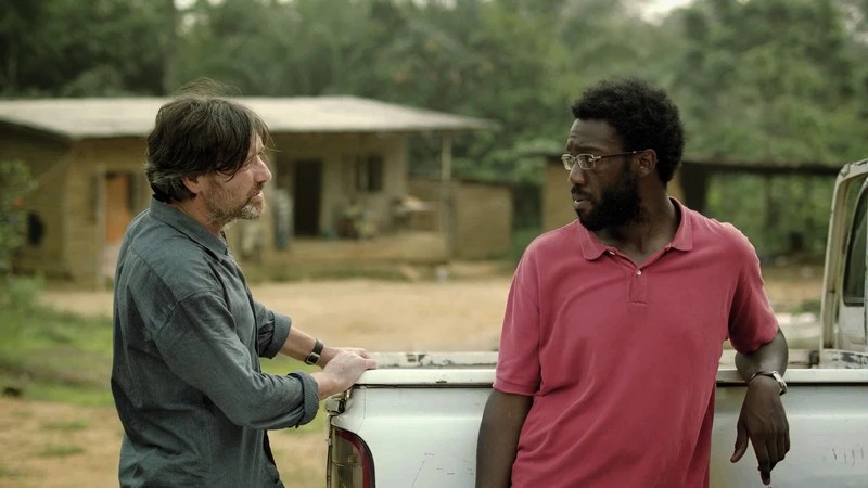 Ebbo (Pierre Bokma) talking to Alex (Jean-Christophe Folly) leaning against a car.