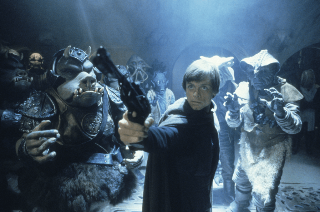 Luke (Mark Hamill) pointing a gun with various aliens around him.
