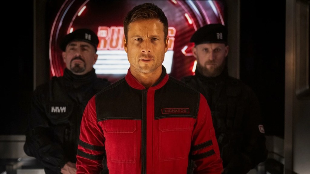 Ben Richards (Glen Powell) in a red jumpsuit that marks him as a contestant on The Running Man.