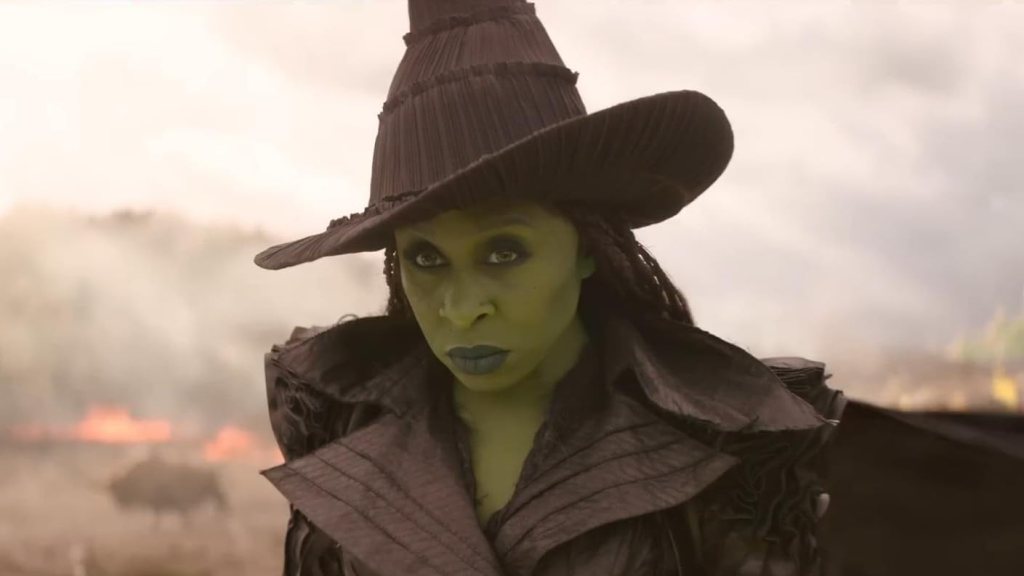 Elphaba (Cynthia Erivo) looking fierce. Behind her, something is burning.