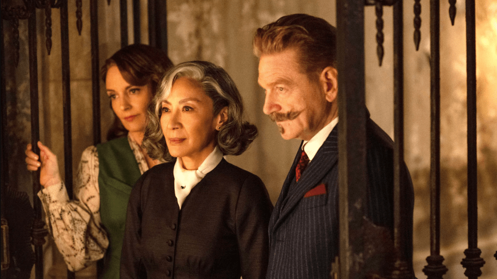 Ariadne (Tina Fey), Joyce (Michelle Yeoh) and Poirot (Kenneth Branagh) standing in an open wrought iron gate.