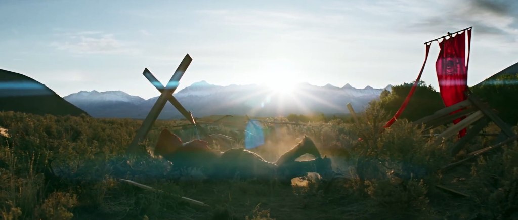 A knight lying on the ground next to an off-kilter cross and a red flag.