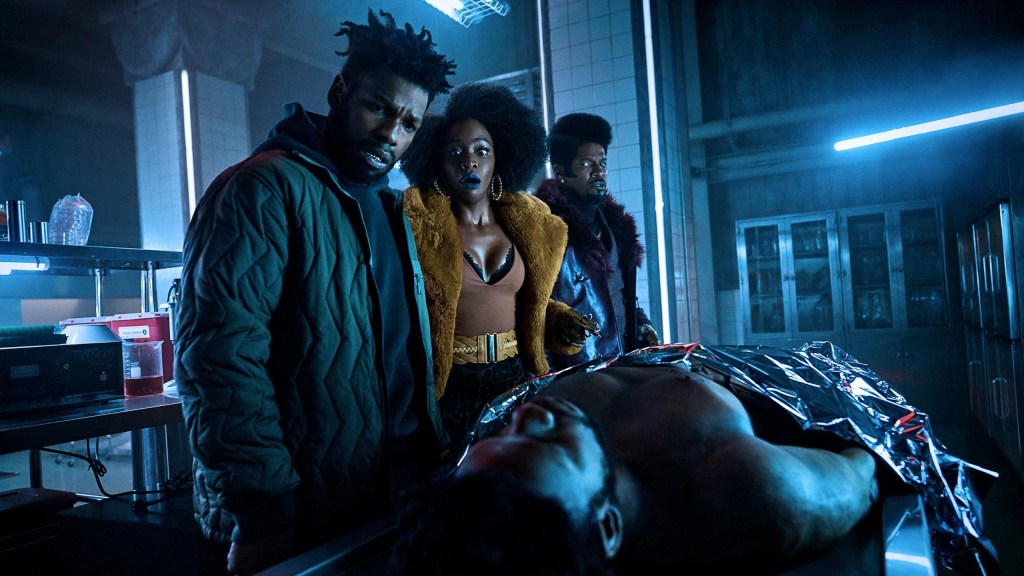 Fontaine (John Boyega), Yo-Yo (Teyonah Parris) and Slick Charles (Jamie Foxx) looking at a dead body that looks exactly like Fontaine.