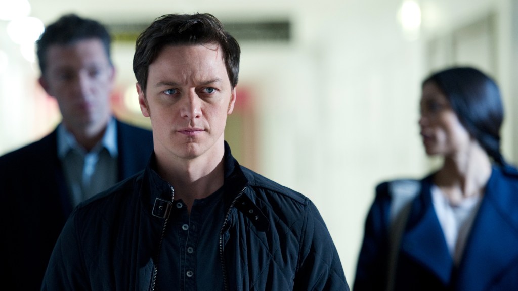 Simon (James McAvoy) looking serious, Franck (Vincent Cassel) and Elizabeth (Rosario Dawson) blurry behind him.