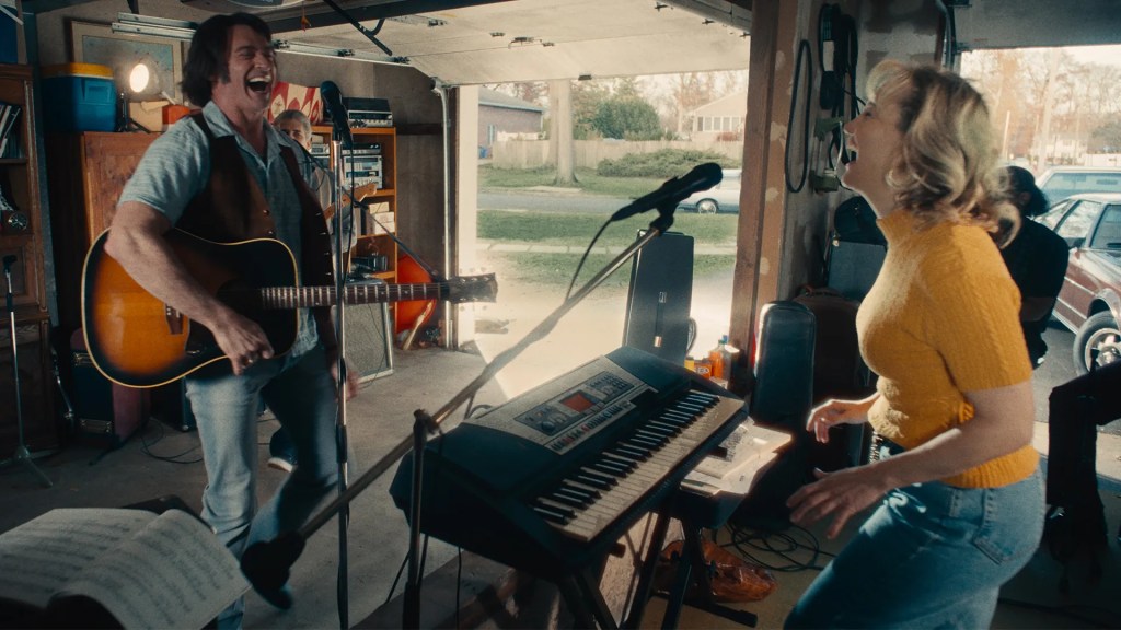 Mike (Hugh Jackman) and Claire (Kate Hudson) laughing at each other at a band rehearsal in their garage.