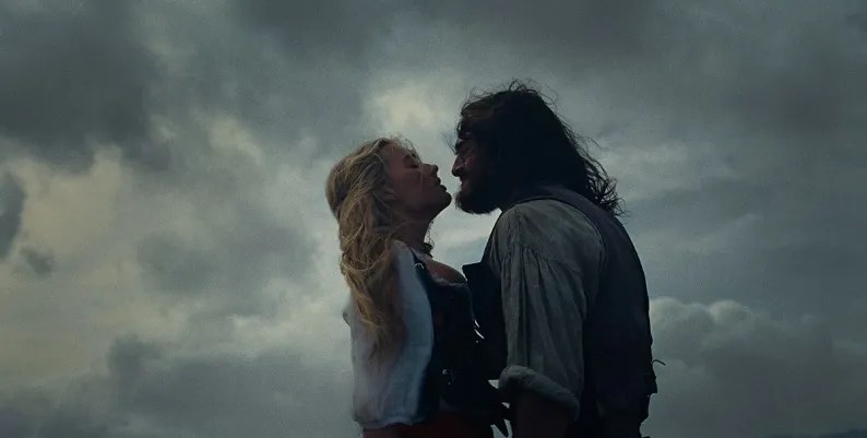 Heathcliff (Jacob Elordi) lifting Catherine (Margot Robbie) towards his face by her corset strings.