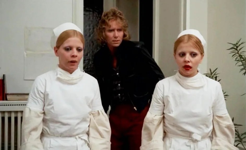 Frédérich (Jean-Loup Philippe) standing behind two vampire sisters dressed as nurses (Catherine Castel, Marie-Pierre Castel).