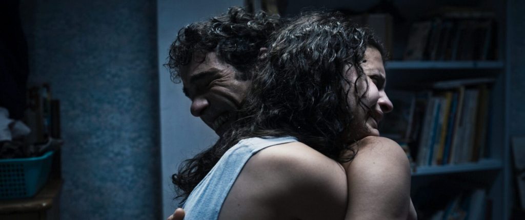 Alpha (Mélissa Boros) and Amin (Tahar Rahim) holding on to each other tightly, their faces contorted in pain, grief.