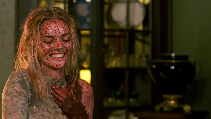 Grace (Samara Weaving) smiling broadly with blood all over her face and hair. 