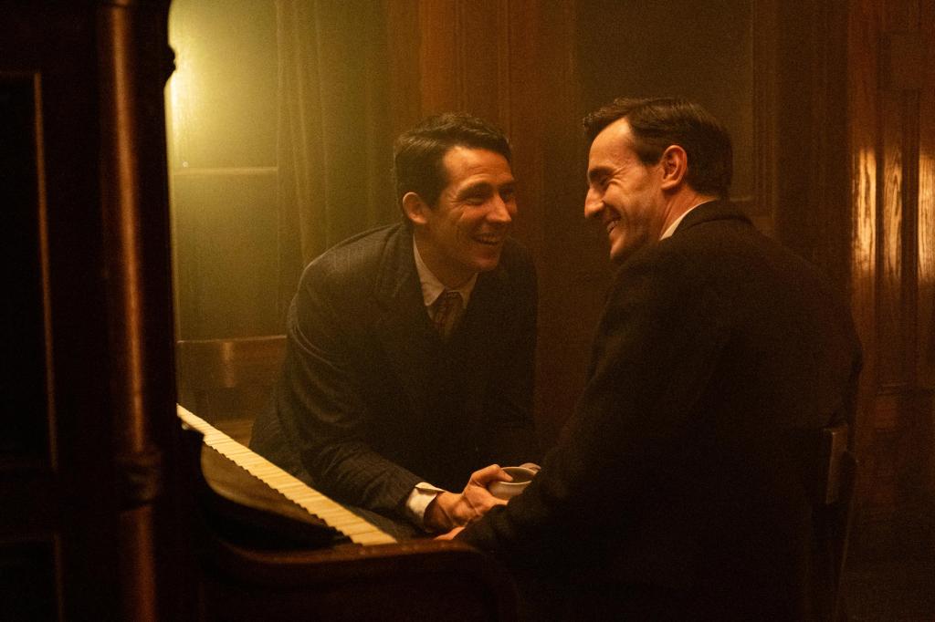 Lionel (Paul Mescal) and David (Josh O'Connor) sitting next to a piano, smiling broadly at each other.