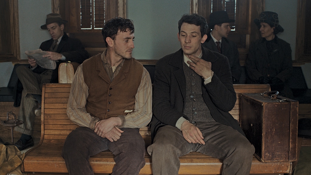 Lionel (Paul Mescal) and David (Josh O'Connor) sitting in a train station, looking a little sad and wearied.