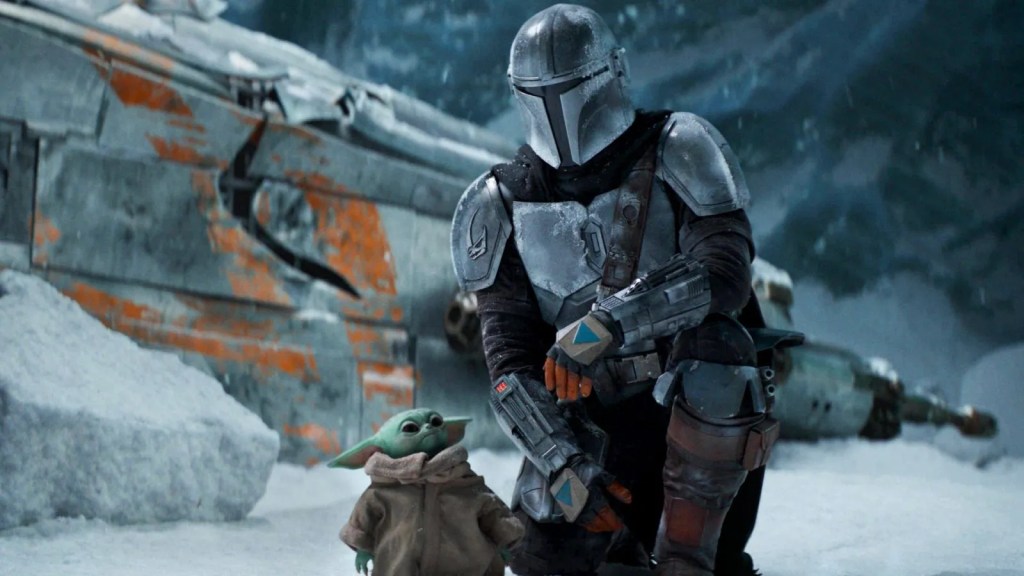 Grogu and Mando in a snow landscape, a battered spaceship behind them. 